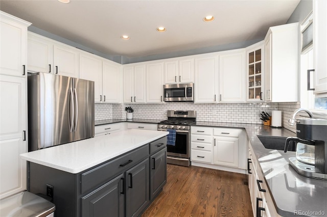 kitchen with white cabinets, a kitchen island, dark hardwood / wood-style flooring, stainless steel appliances, and sink