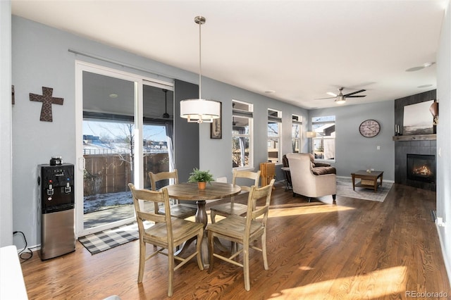 dining space with ceiling fan, a fireplace, and wood-type flooring