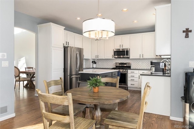 kitchen with dark wood-type flooring, pendant lighting, stainless steel appliances, and white cabinetry