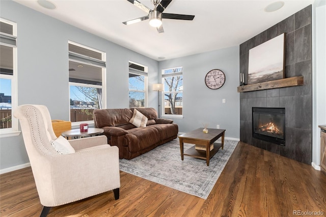 living room featuring ceiling fan, a tile fireplace, and dark hardwood / wood-style flooring