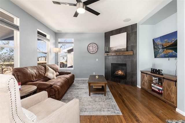 living room featuring dark wood-type flooring, a tile fireplace, and ceiling fan