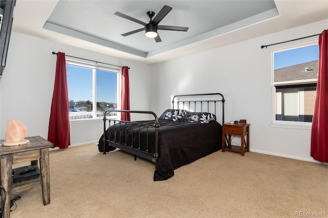 carpeted bedroom with ceiling fan and a raised ceiling