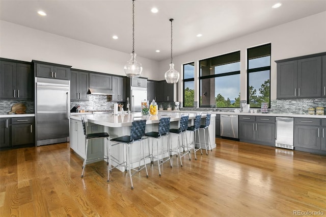 843 Long Timber Ln, Monument, CO 80132 - kitchen with appliances with stainless steel finishes, tasteful backsplash, light countertops, a breakfast bar, and recessed lighting
