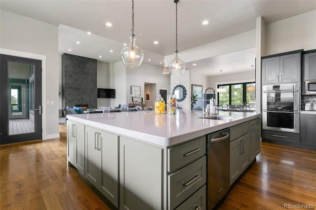 843 Long Timber Ln, Monument, CO 80132 - kitchen featuring appliances with stainless steel finishes, a spacious island, open floor plan, light countertops, and dark wood-style flooring