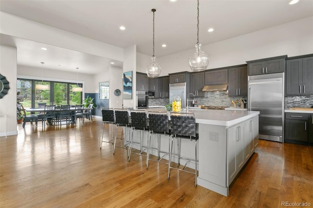 843 Long Timber Ln, Monument, CO 80132 - kitchen with stainless steel appliances, decorative backsplash, light countertops, light wood-style flooring, and recessed lighting