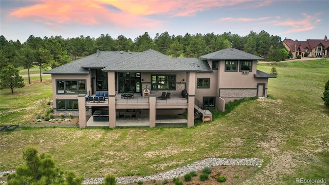 843 Long Timber Ln, Monument, CO 80132 - back of property at dusk featuring a patio area, stucco siding, a yard, roof with shingles, and a wooden deck