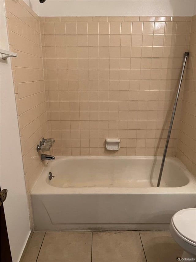 bathroom featuring toilet, tiled shower / bath combo, and tile patterned floors