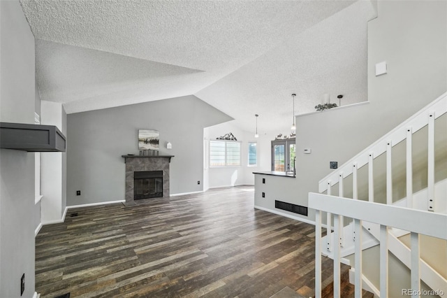 68 N Quicksilver Ave, Castle Rock, CO 80104 - unfurnished living room with a textured ceiling, dark wood-style flooring, lofted ceiling, a tile fireplace, and stairway