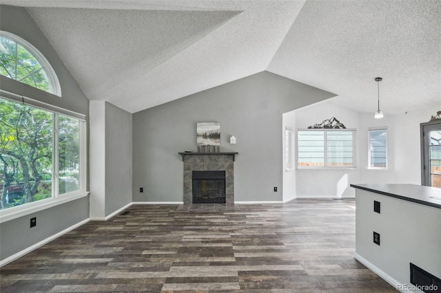 68 N Quicksilver Ave, Castle Rock, CO 80104 - unfurnished living room with a textured ceiling, lofted ceiling, dark wood-type flooring, a tile fireplace, and healthy amount of natural light
