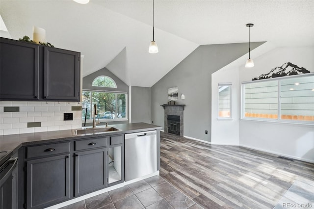 68 N Quicksilver Ave, Castle Rock, CO 80104 - kitchen with stainless steel dishwasher, a sink, dark countertops, vaulted ceiling, and a tiled fireplace