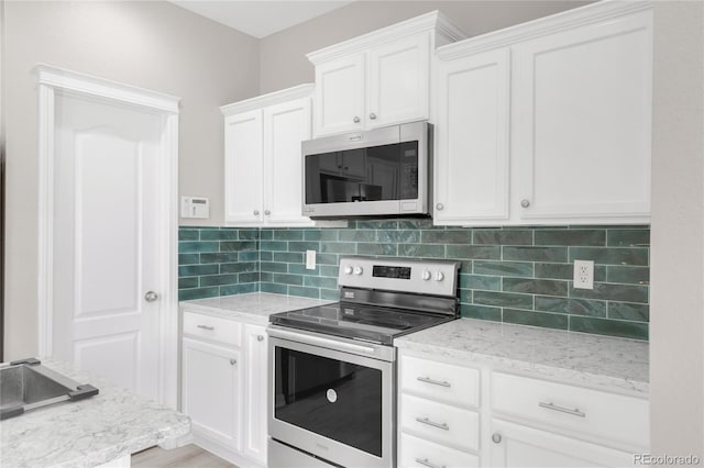 186 S 45th Ave, Brighton, CO 80601 - kitchen with appliances with stainless steel finishes, backsplash, white cabinetry, and light stone counters