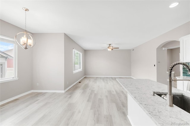 186 S 45th Ave, Brighton, CO 80601 - unfurnished dining area featuring a ceiling fan, light wood-style floors, arched walkways, and a chandelier