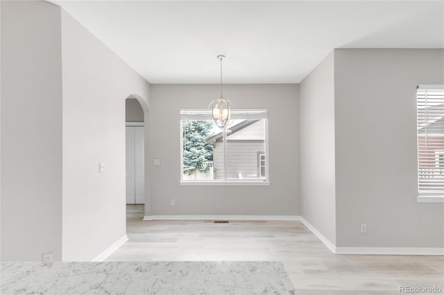 186 S 45th Ave, Brighton, CO 80601 - unfurnished dining area featuring arched walkways, light wood-style flooring, and a chandelier