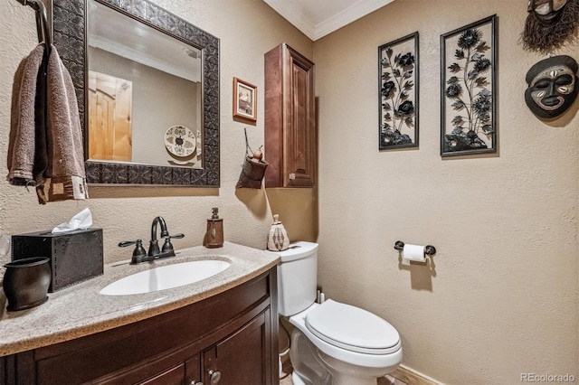 bathroom featuring toilet, vanity, crown molding, and a textured wall