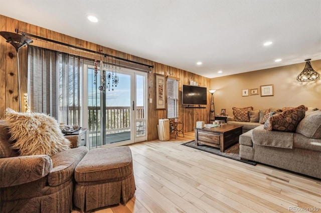 living room featuring light wood finished floors, wooden walls, and recessed lighting