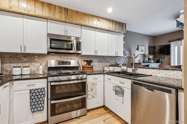 kitchen featuring appliances with stainless steel finishes, white cabinetry, a sink, and tasteful backsplash