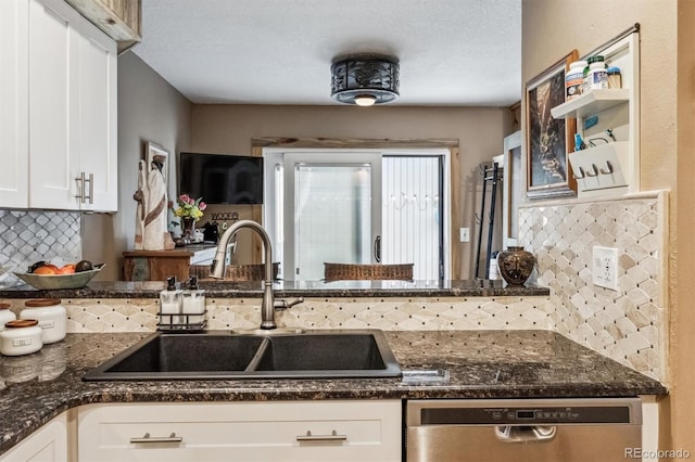 kitchen with tasteful backsplash, dark stone counters, white cabinets, dishwasher, and a sink