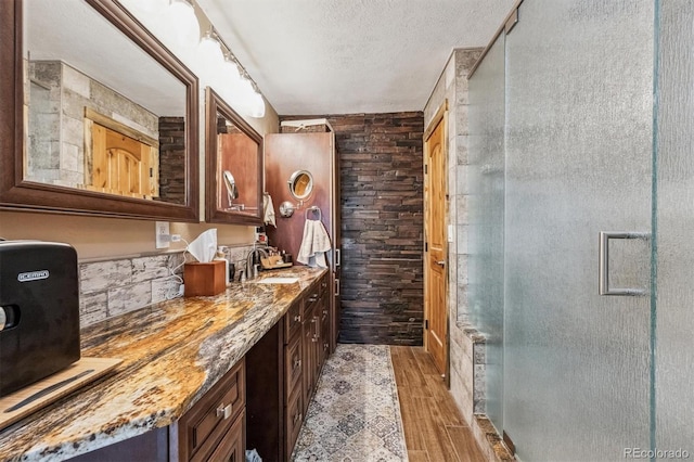 bathroom with a shower stall, a textured ceiling, wood finished floors, and vanity