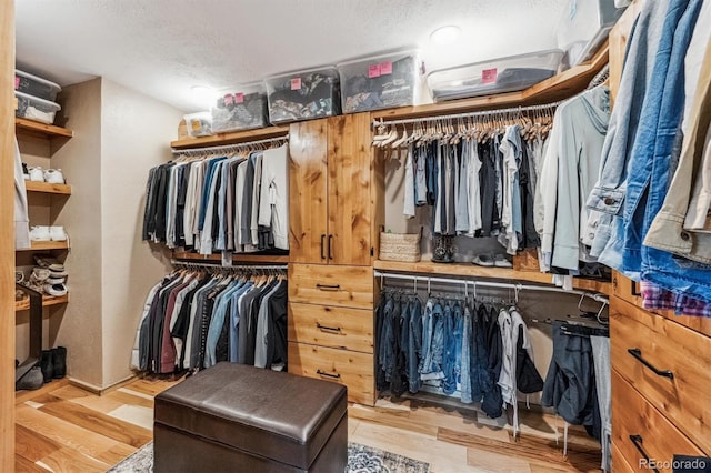 walk in closet with light wood-style floors and built in desk