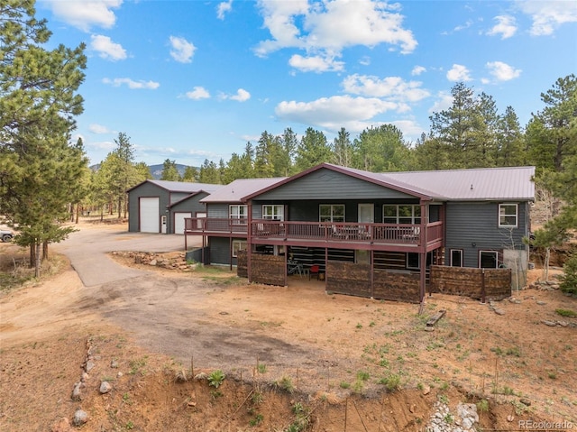 50 Rd P78, Bailey, CO 80421 - view of front of home with a garage, a wooden deck, metal roof, concrete driveway, and an outbuilding