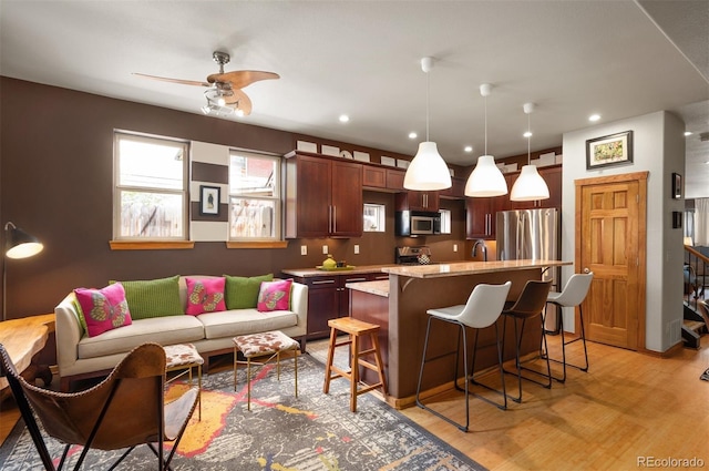 469 Elati St, Denver, CO 80204 - kitchen featuring light wood-style floors, appliances with stainless steel finishes, a breakfast bar, and recessed lighting