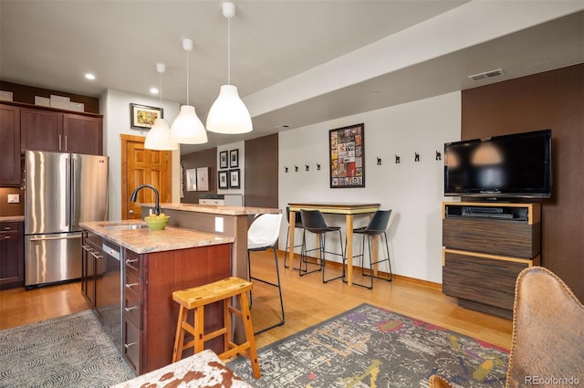 469 Elati St, Denver, CO 80204 - kitchen with visible vents, a kitchen breakfast bar, a sink, light wood-style flooring, and stainless steel appliances