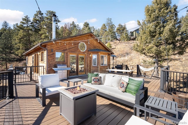 wooden terrace featuring a grill and an outdoor living space with a fire pit