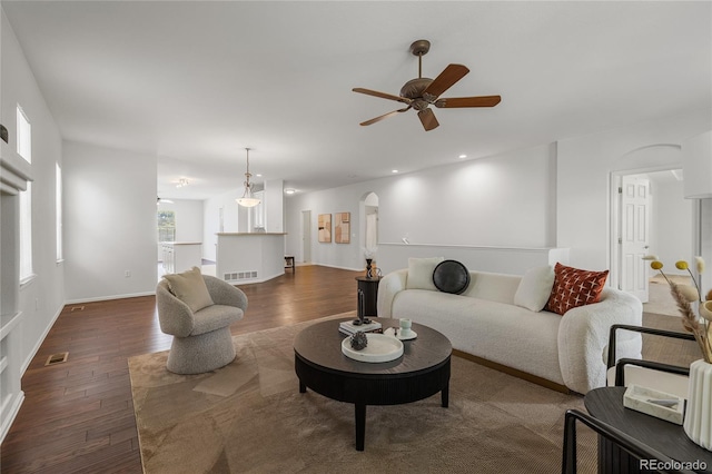23421 E Long Pl, Aurora, CO 80016 - living area featuring dark wood-style flooring, arched walkways, ceiling fan, and plenty of natural light