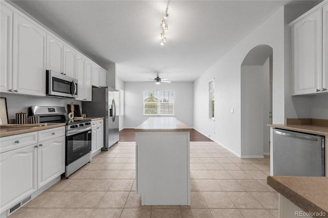 23421 E Long Pl, Aurora, CO 80016 - kitchen with stainless steel appliances, a kitchen island, a ceiling fan, white cabinets, and arched walkways