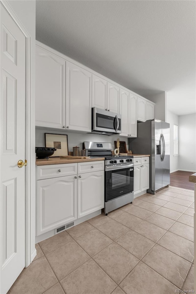 23421 E Long Pl, Aurora, CO 80016 - kitchen featuring appliances with stainless steel finishes, light tile patterned flooring, white cabinets, and a textured ceiling