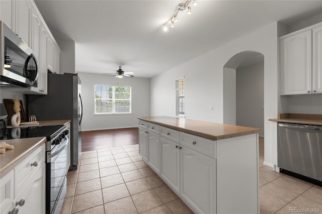 23421 E Long Pl, Aurora, CO 80016 - kitchen with stainless steel appliances, arched walkways, a center island, a ceiling fan, and light tile patterned floors