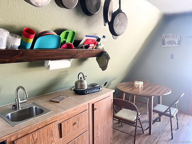 kitchen featuring sink, light wood-type flooring, and tile counters