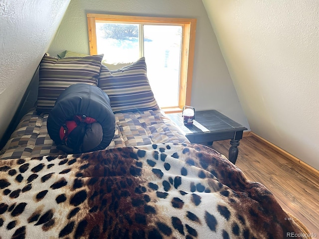 bedroom featuring hardwood / wood-style flooring, a textured ceiling, and lofted ceiling