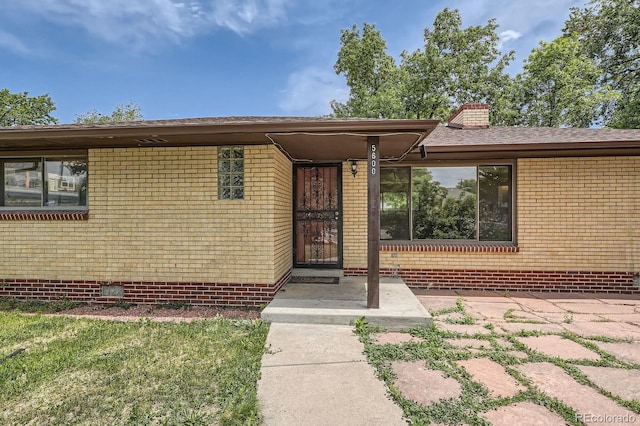 5600 Dover St, Arvada, CO 80002 - doorway to property featuring brick siding and a chimney
