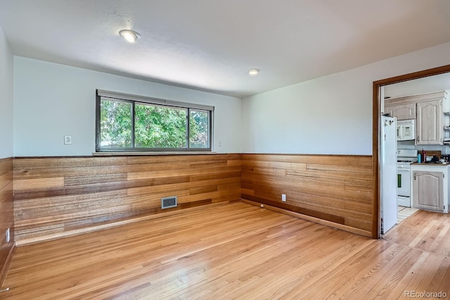 5600 Dover St, Arvada, CO 80002 - unfurnished room with light wood finished floors, a wainscoted wall, and wooden walls