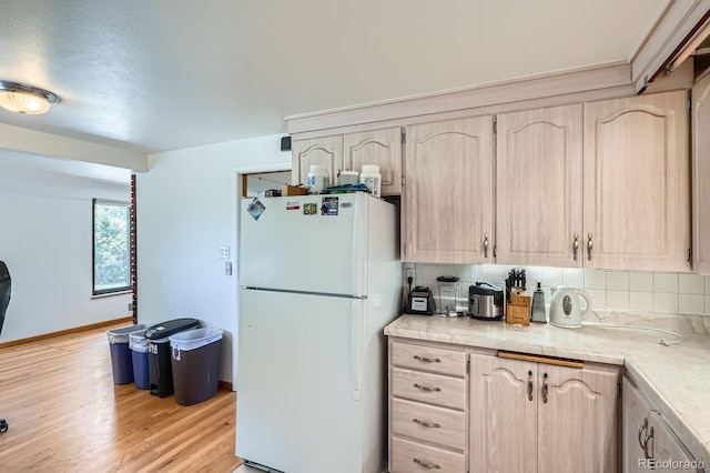 5600 Dover St, Arvada, CO 80002 - kitchen featuring freestanding refrigerator, light brown cabinetry, decorative backsplash, light wood-type flooring, and baseboards