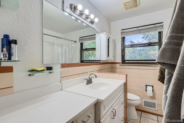 5600 Dover St, Arvada, CO 80002 - bathroom featuring vanity, tile patterned floors, toilet, tile walls, and a textured wall