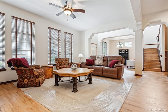 living room featuring ceiling fan with notable chandelier, light hardwood / wood-style floors, and a healthy amount of sunlight