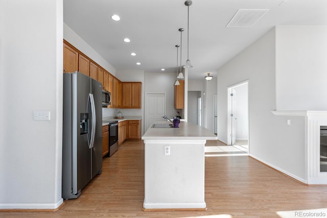 kitchen featuring visible vents, light wood finished floors, a sink, stainless steel appliances, and light countertops