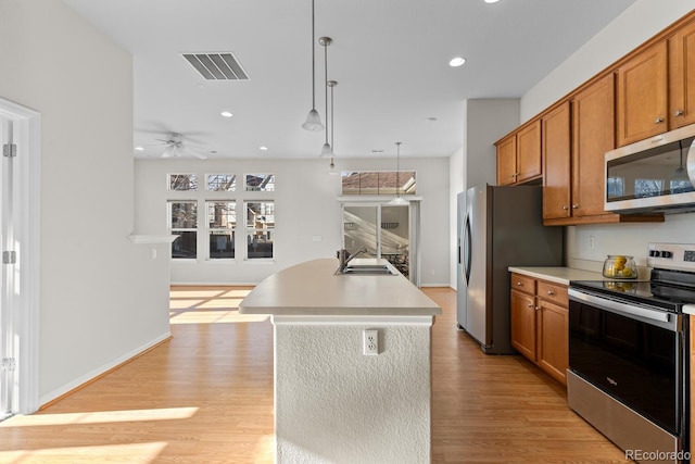 kitchen featuring visible vents, light countertops, light wood-style flooring, brown cabinetry, and stainless steel appliances