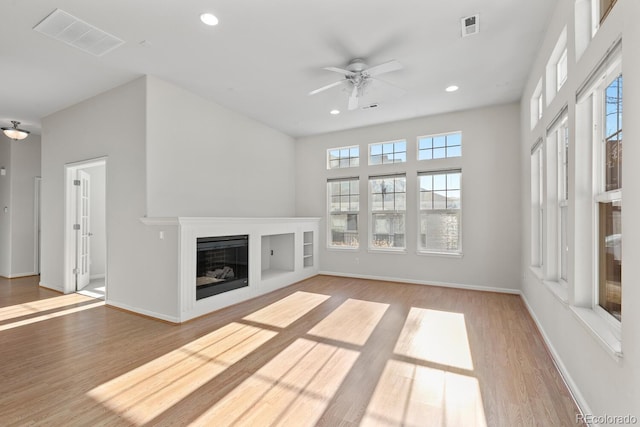 unfurnished living room featuring recessed lighting, visible vents, light wood-style floors, and a glass covered fireplace