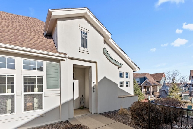 exterior space featuring roof with shingles and stucco siding