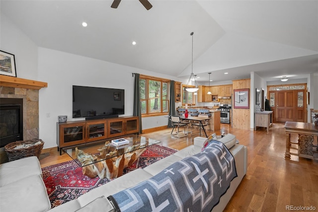 27711 Moffat Rd, Evergreen, CO 80439 - living area featuring light wood-style floors, a ceiling fan, high vaulted ceiling, and a tile fireplace