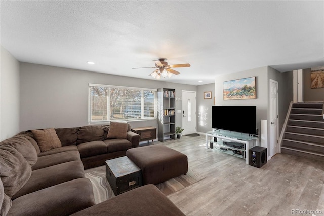 living room featuring ceiling fan, light hardwood / wood-style floors, and a textured ceiling