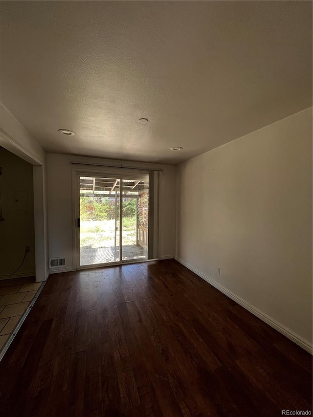 empty room with a textured ceiling and dark hardwood / wood-style flooring