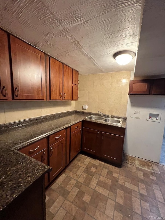 kitchen featuring sink, dark stone counters, and backsplash