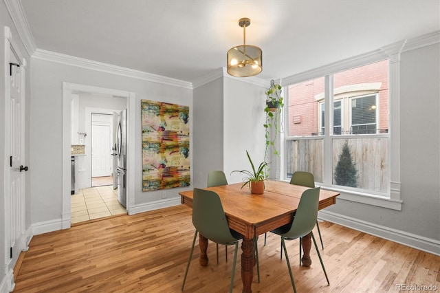 dining room with crown molding and light hardwood / wood-style flooring