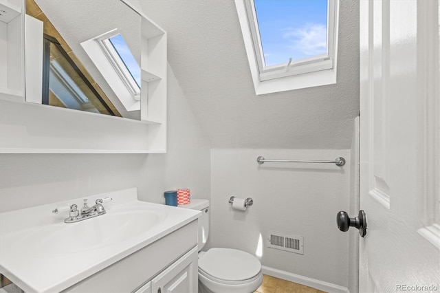 bathroom featuring vanity, lofted ceiling, and toilet