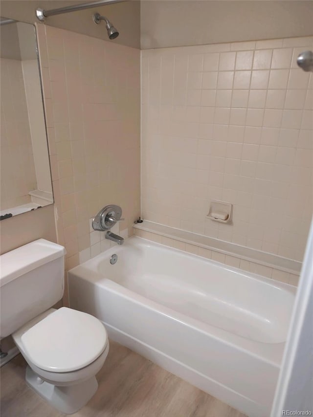 bathroom featuring tiled shower / bath, hardwood / wood-style floors, and toilet