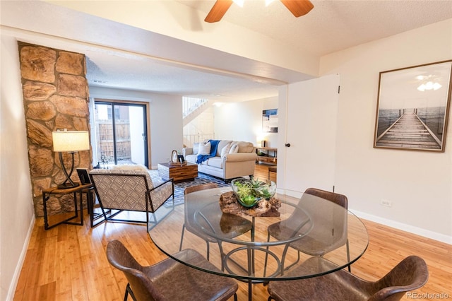 living area featuring ceiling fan, baseboards, light wood-type flooring, and a textured ceiling